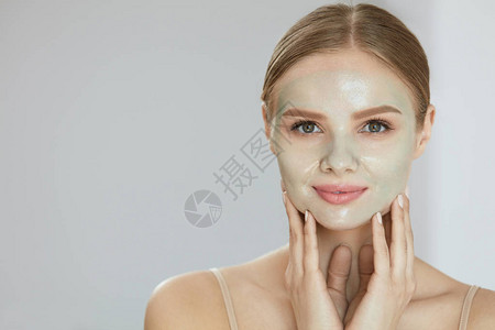 化妆面罩漂亮笑的年轻美少女穿着面纱的近身肖像皮肤护理产品在脸部上贴图片