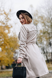 穿着海沟大衣和帽子的漂亮时装女士在秋天公园散步图片
