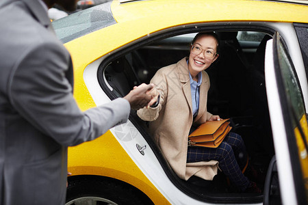 帮助年轻笑的亚裔女走出租车手牵着她的身影图片