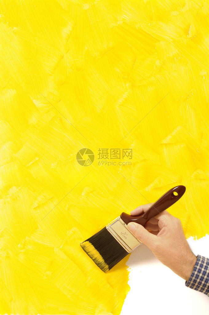 男人拿着画笔有部分完成的黄色空白墙图片