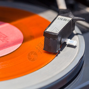 橙色黑胶唱片上转盘的唱臂特写图片