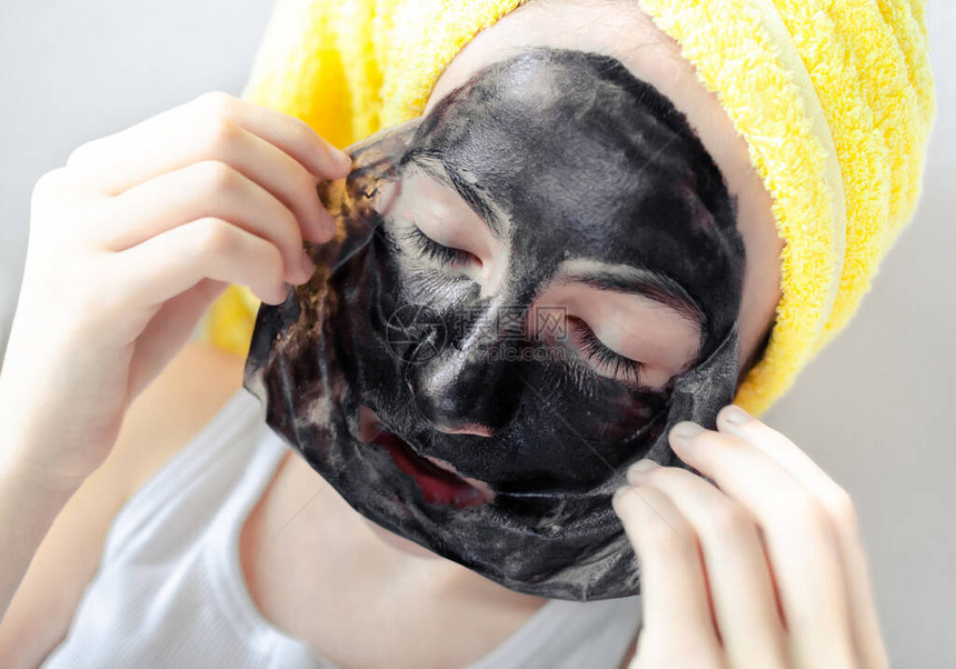 女孩把黑面皮从面具上摘下来的近身肖像Spa美容孔隙净化治疗皮肤护理图片