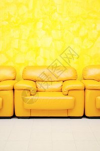 候诊室的黄色皮革扶手椅和黄色纹理墙壁图片