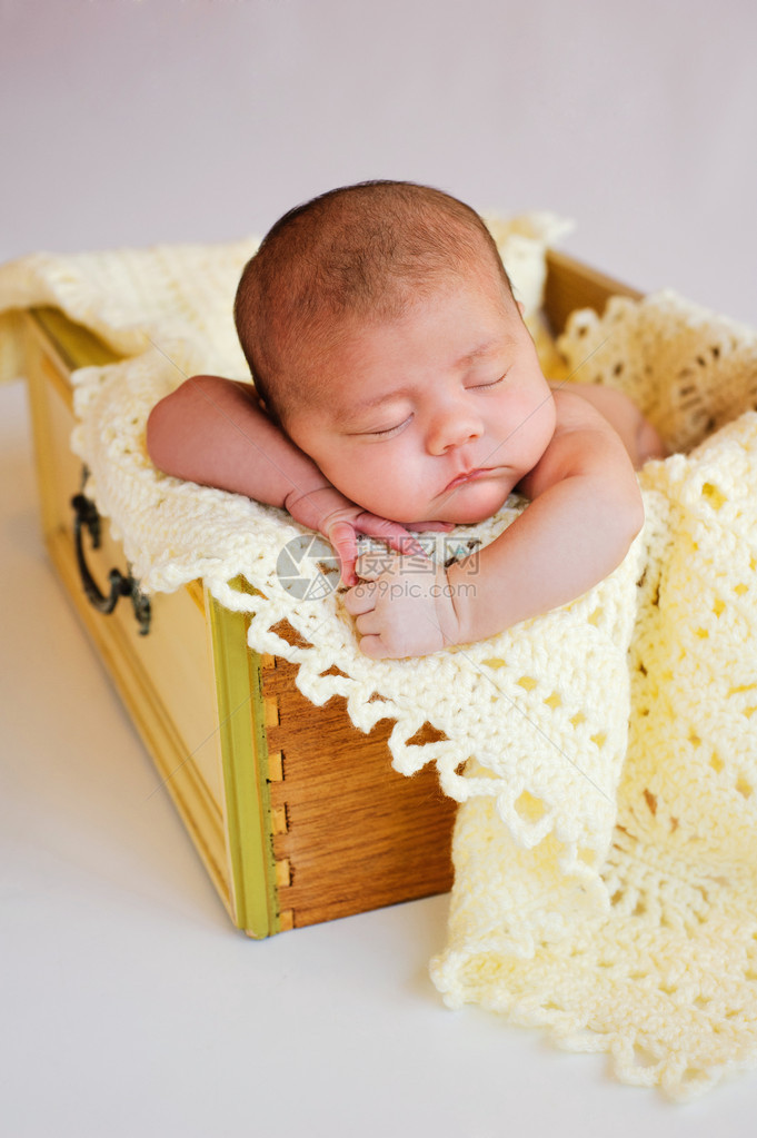 刚出生的女婴睡在一个老式的黄色抽屉里图片