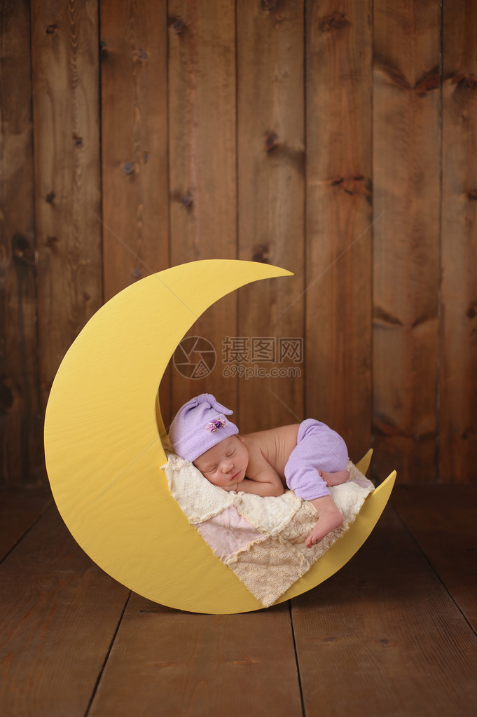 一个十一天大的新生女婴穿着睡衣和睡帽的工作室肖像她睡在一个月亮图片