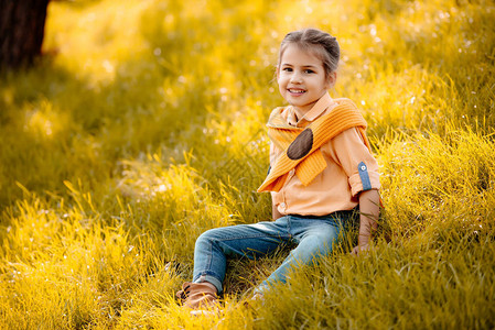 小微笑的孩子坐在秋天的草地上图片