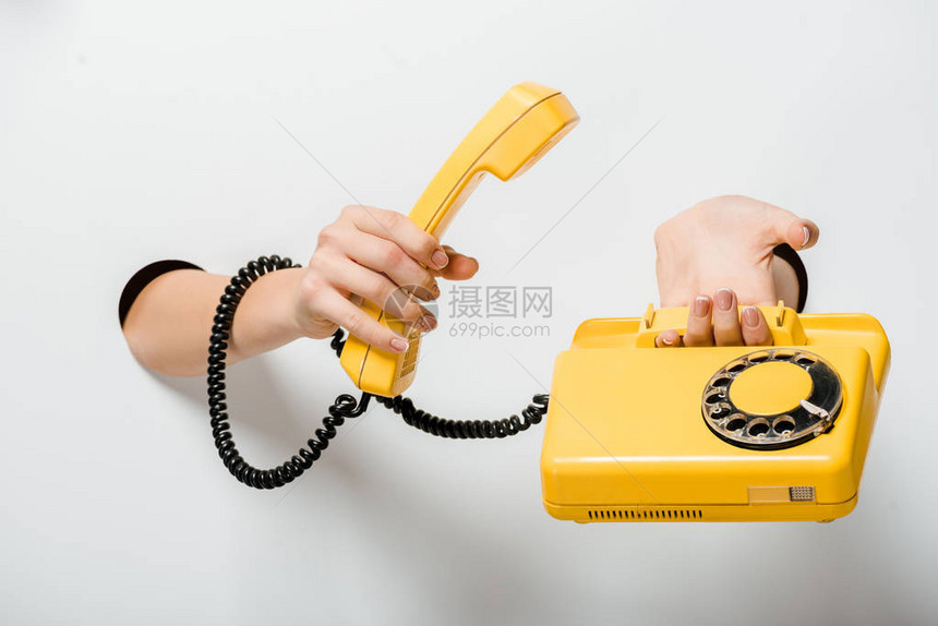 妇女通过白色洞口持反黄色固定式电话的妇女的作物图象图片
