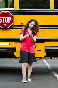 年轻女孩从校车上走开的垂直照片图片