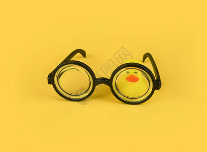 黄色背景圆框眼镜和黄色橡皮鸭的有趣护目镜愚人节贺卡概念教育上学时图片