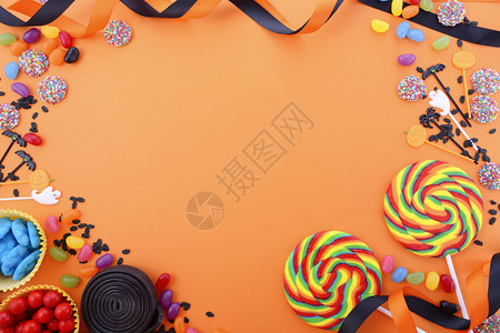 万圣节或儿童生日糖果在明亮的橙色背景上倾斜图片