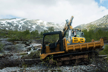 从事挪威山上道路建设工作的黄色挖掘机图片