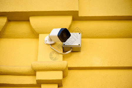 黄色建筑立面上安全摄像头的近景背景图片