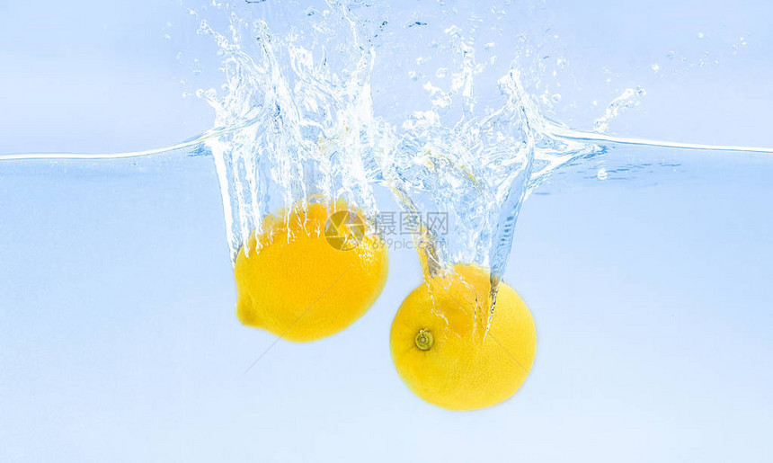 新鲜柠檬沉入水中溅起水花蓝色背景图片