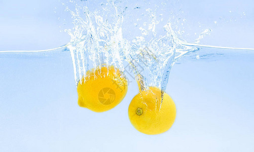 新鲜柠檬沉入水中溅起水花蓝色背景图片