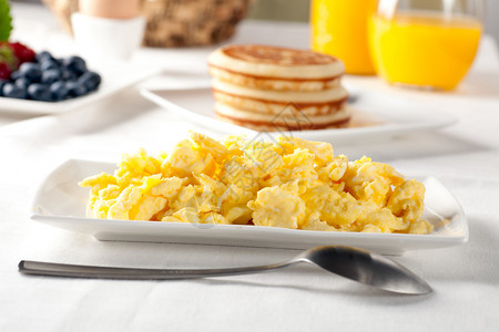 新鲜的炒鸡蛋和早午餐桌上的勺子图片