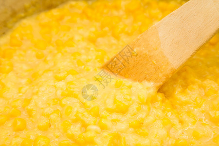 用木勺搅拌一锅热乎的奶油玉米图片