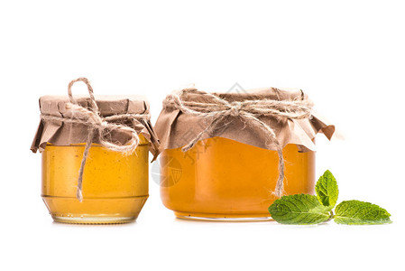 玻璃罐中新鲜蜂蜜和白色隔离的绿图片