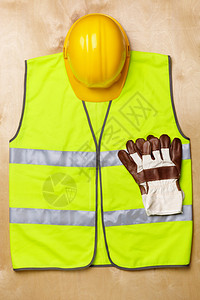 带有黄色安全帽和木质纹理制服的工业概念图片