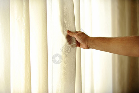 一个人的手拉着窗帘让温暖的图片