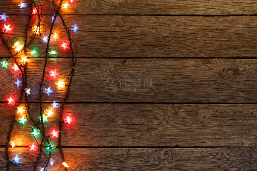 圣诞灯节假日亮光的加兰边界对浅棕褐木板表面的顶视角Xma树装饰图片