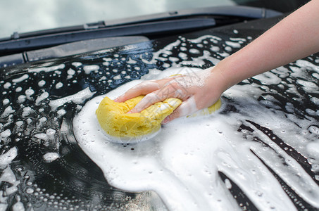 用黄色海绵洗车的女手图片