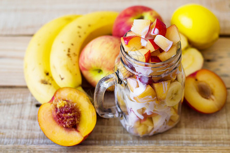 水果沙拉与玻璃罐中酸奶和各种木制水果的横向相照图片