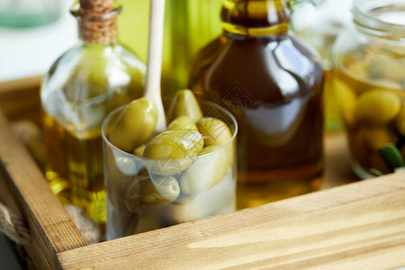 用勺子和绿橄榄罐子木盘上的各种芳香橄榄油瓶近图片