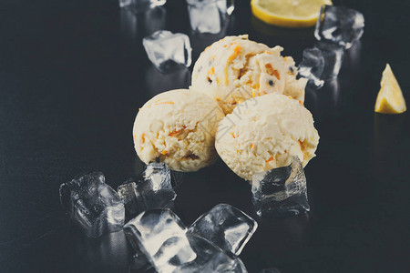 冰淇淋勺加冰块和柠檬片在黑色背景上美味的冷甜图片