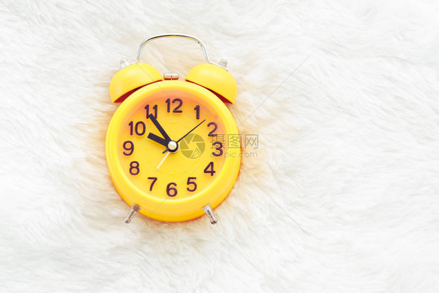 白羊毛晚和懒惰时间概念的黄色闹钟图片