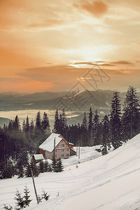 在多雪的冬天山的美丽的日落与木房子图片