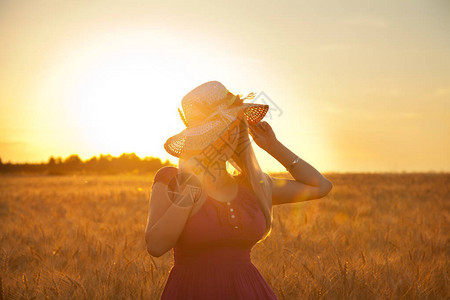美丽的金发美女白草帽在日落时图片