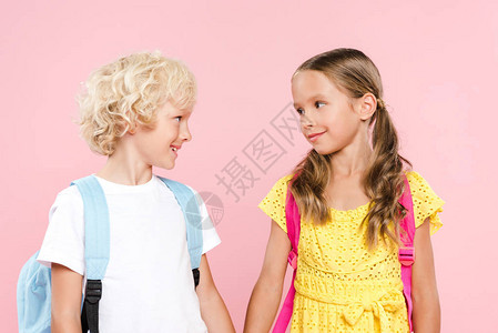 带着背包看着彼此的微笑的学童在粉红图片