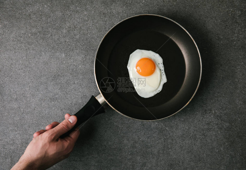 以灰色煎锅和煎蛋的人图片