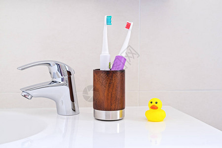 洗手间黄色橡皮鸭子水槽上木玻璃两张电动牙刷图片