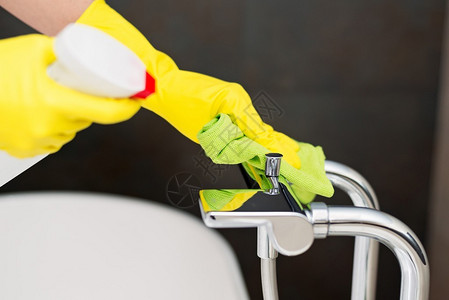 使用黄色橡胶防护手套清洗浴缸搅拌器的女图片