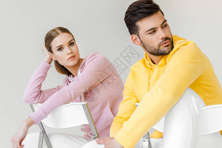 粉红和黄色帽衫中男女模和女模坐在白边图片