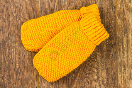 木制背景上的黄色针织手套图片