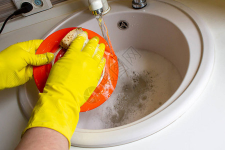 用黄色手套洗碗男人的手图片