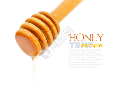 蜂蜜从白色背景上孤立的木勺上滴下来图片
