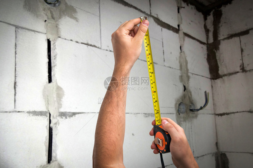 以厘米和足脚测量黄带度的工人测量到新建墙壁与砖瓦之间图片