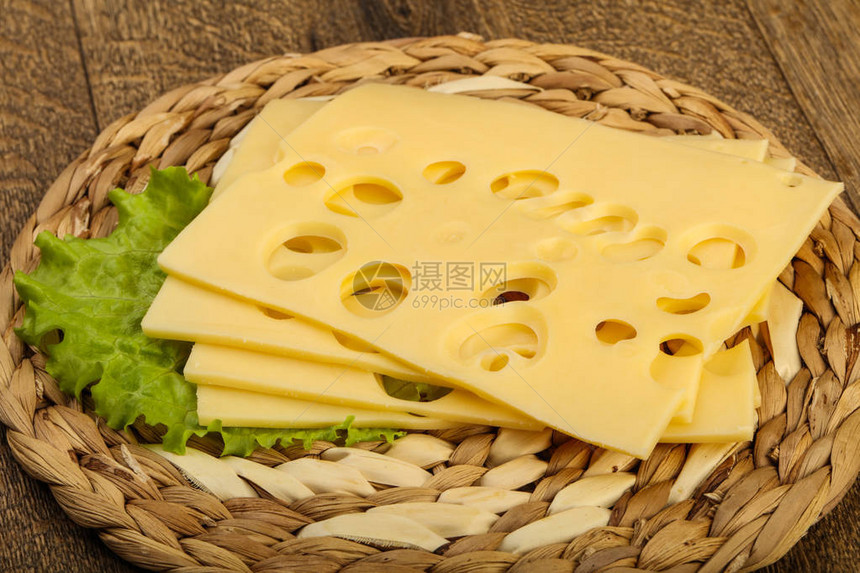 木质背景上带有沙拉叶的美味切片奶酪图片