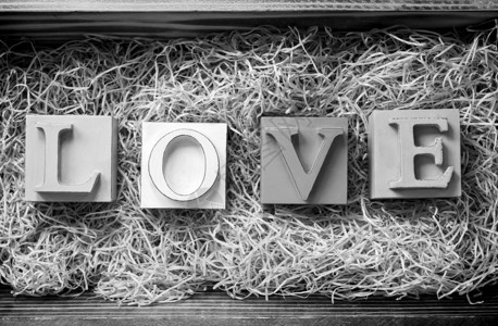 爱这个词用大块字母拼写在一个木制礼物盒里装满了黑色和图片