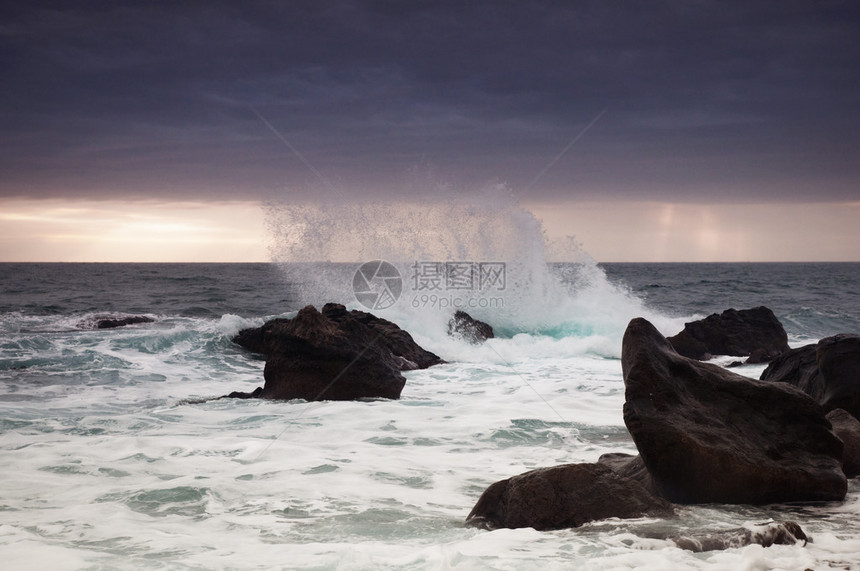 海上风暴海岸附近的岩石上出现大浪图片