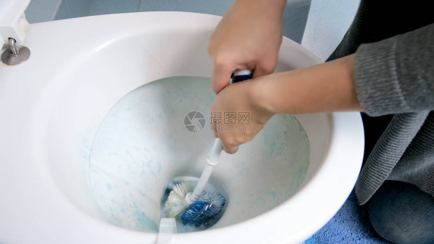 女手用刷子清洁马桶的特写照片图片