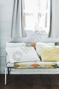 窗前有白色和蜜蜂枕头的沙发还有图片