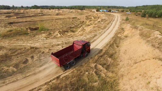 宝马x6用于在地面采石场驾驶的红色大卡车的空中飞行背景