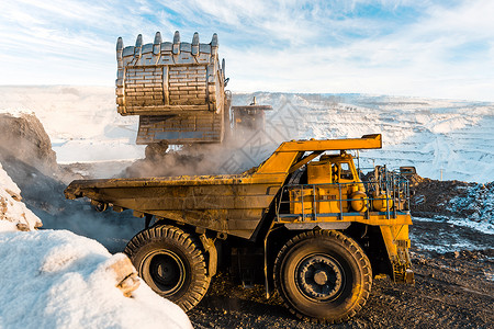 大型采石场自卸车将岩石装入自卸车将煤炭装载到车身工作卡车中采矿卡车采矿机械背景图片