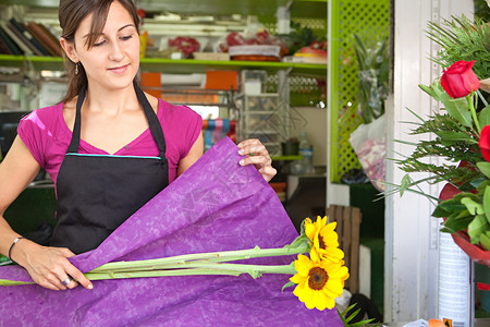 迷人的花店老板女人在她的花卉市场商店的柜台工作图片