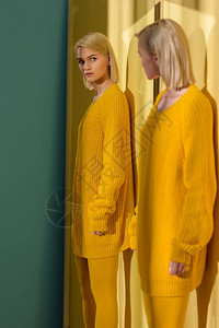 穿着黄色毛衣和紧身裤的金发女人在镜子里图片