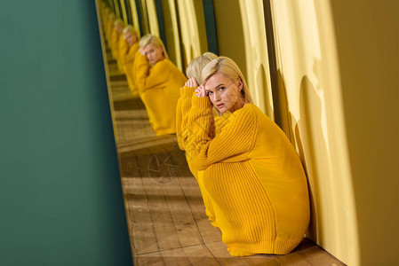 穿着黄色毛衣的美丽深思美貌的女人的一面背景图片